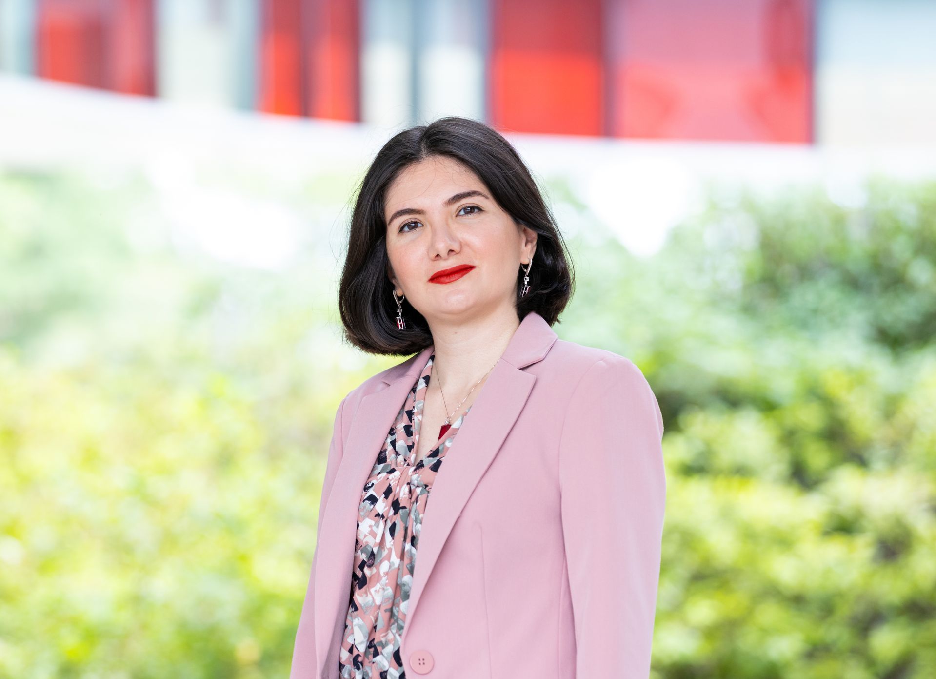 Zohreh Davoudi wears a pink blazer and matching blouse in front of greenery.