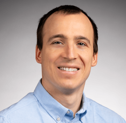 A professional headshot of a smiling man.